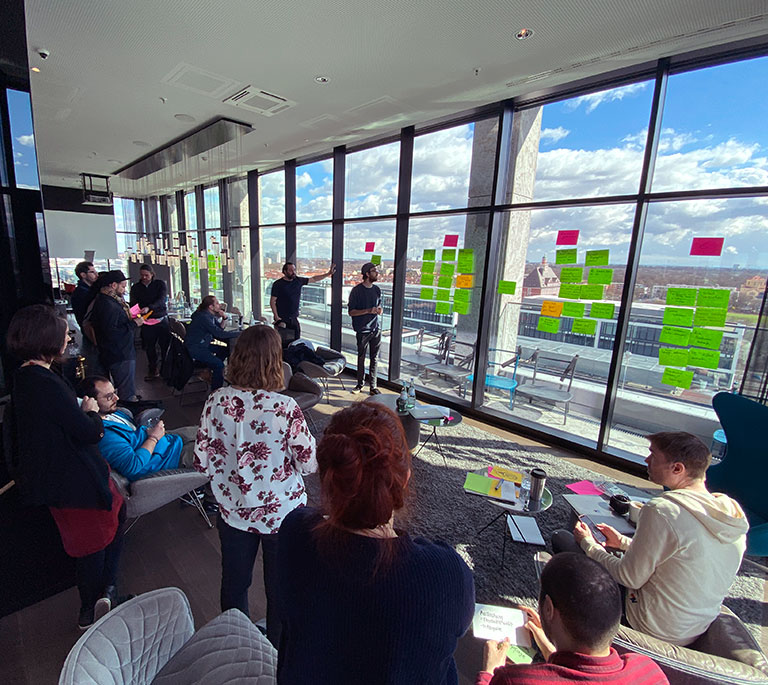 Foto: Workshop mit Teamleads und vielen Postits am Fenster.