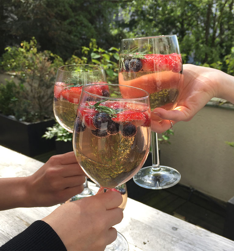 Foto: Mehrerer Team-Mitglieder stoßen mit einem alkoholischen Getränk an.