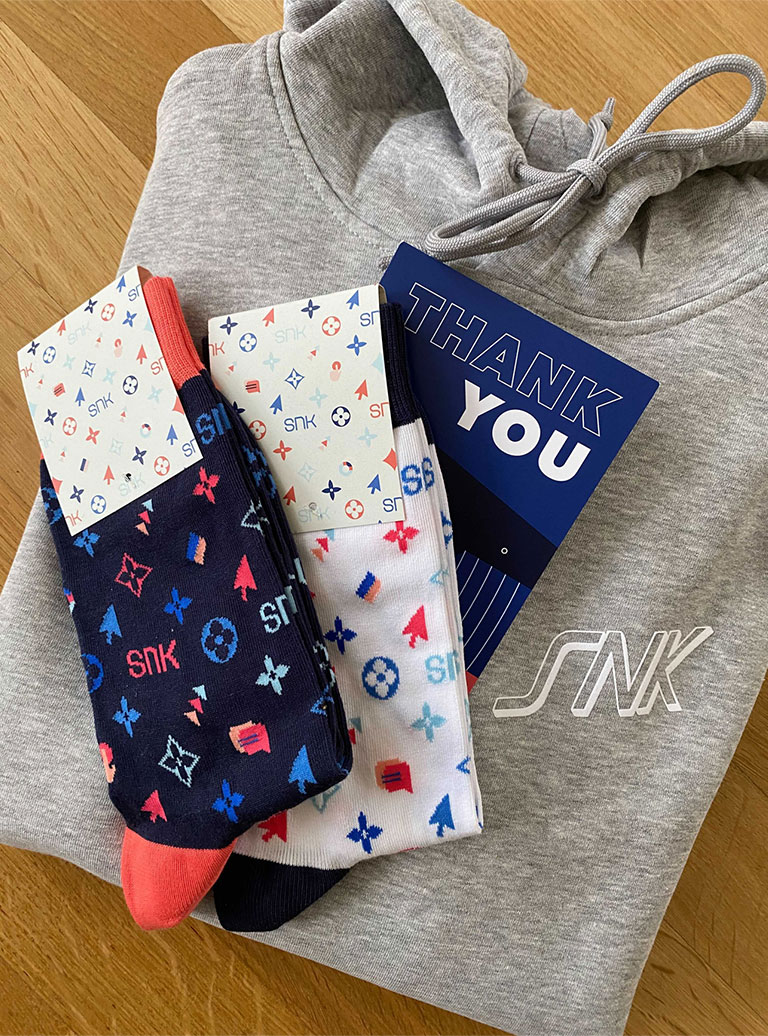 Foto: SNK Merchandise, moderne Socken, eine grauer Hoodie und eine Karte.