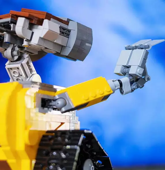 Zu sehen ist das Foto eines kleinen Roboters, der seine Hand hebt.